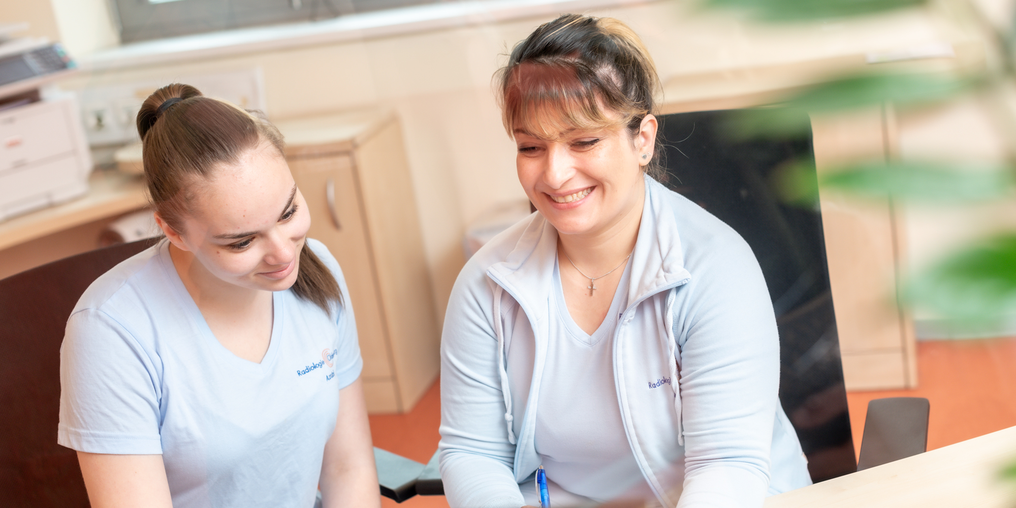 Eine medizinische Fachangestellte erklärt einer Auszubildenden etwas.