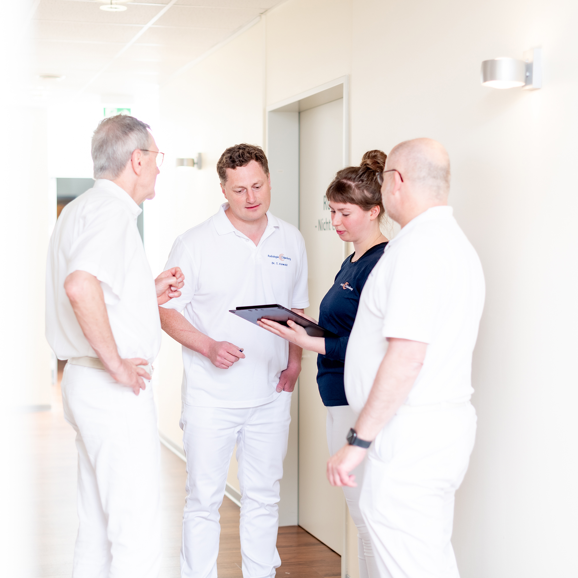 Drei Ärzte der Radiologie und eine medizinische Fachangestellte besprechen Befunde.